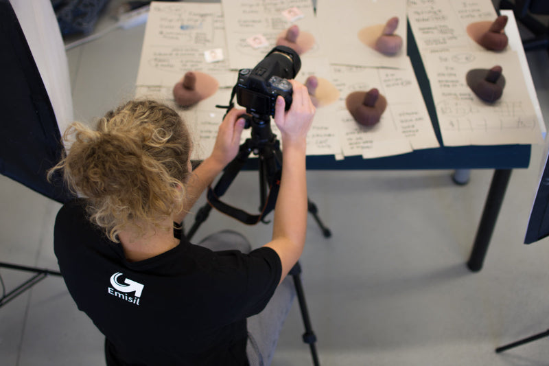 Person taking a photo of a table with Emisil prosthetics and printed materials.
